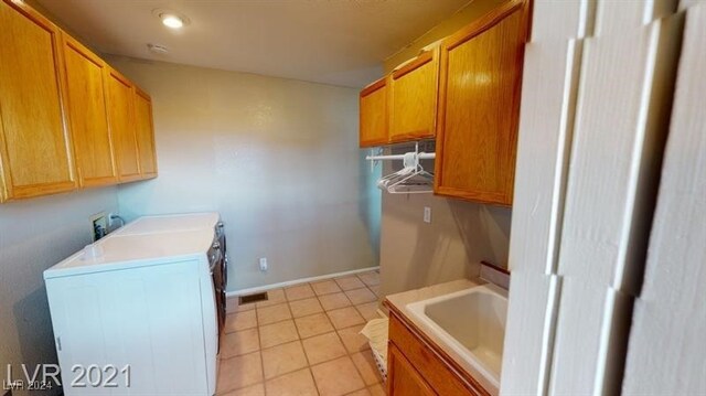 laundry room with cabinets, washer and dryer, sink, and light tile patterned floors