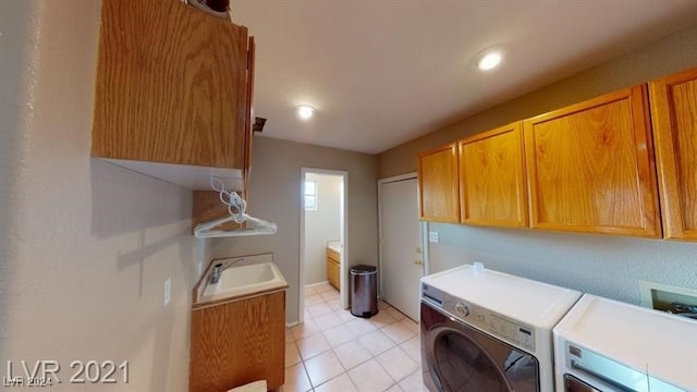 clothes washing area with sink, light tile patterned floors, cabinets, and washing machine and clothes dryer