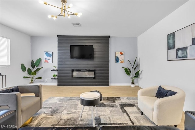 living room featuring a fireplace, wood-type flooring, and an inviting chandelier