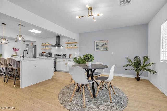 dining room featuring light hardwood / wood-style floors, sink, and a chandelier