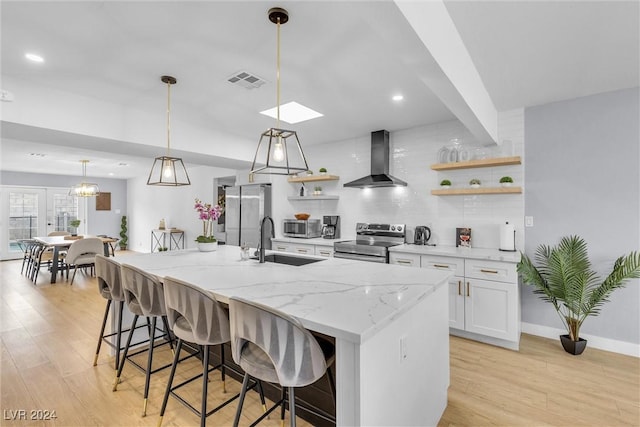 kitchen featuring sink, light hardwood / wood-style flooring, wall chimney exhaust hood, white cabinetry, and stainless steel appliances