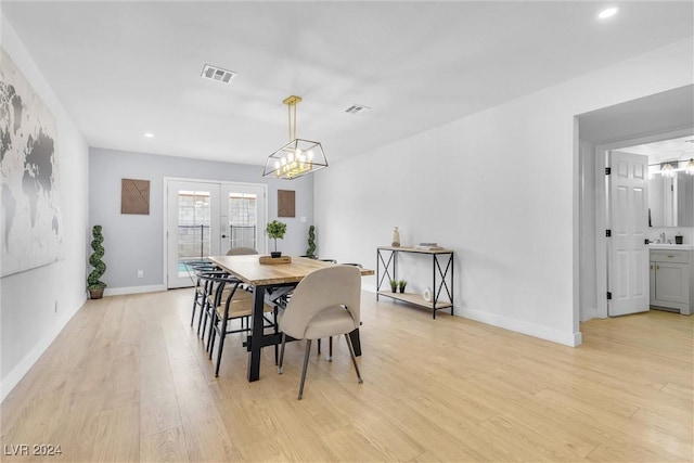 dining room featuring french doors, light hardwood / wood-style floors, a notable chandelier, and sink