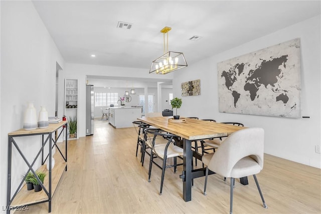 dining space featuring a notable chandelier and light wood-type flooring