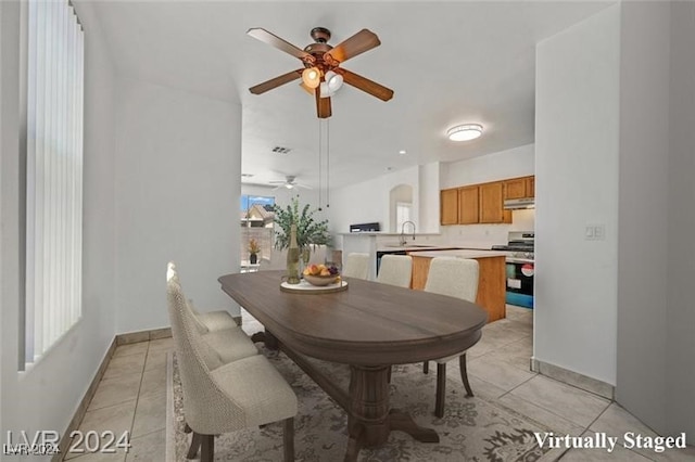 tiled dining room with ceiling fan and sink