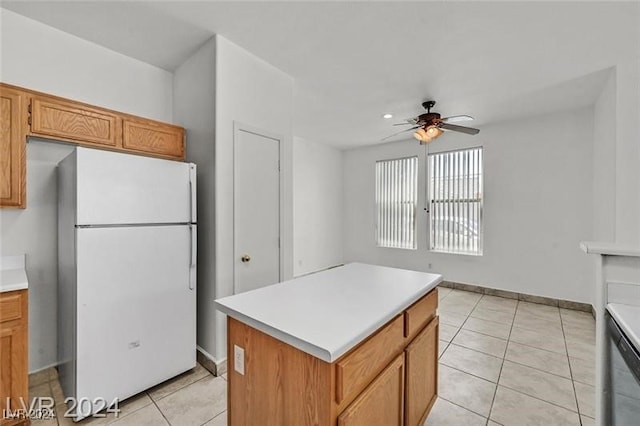 kitchen featuring ceiling fan, a kitchen island, light tile patterned flooring, and white refrigerator