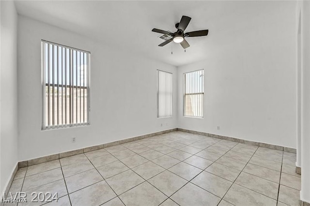 spare room with ceiling fan, a healthy amount of sunlight, and light tile patterned floors