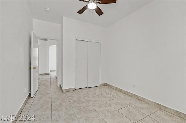 unfurnished bedroom with ceiling fan, a closet, and light tile patterned flooring