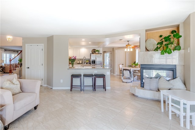 living room featuring a tile fireplace, ceiling fan, and sink