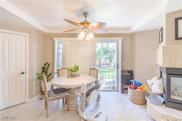 1819 Wild Indigo Ct, Las Vegas, NV 89123 - dining room featuring a premium fireplace, plenty of natural light, a ceiling fan, and a tray ceiling