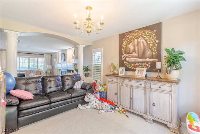 carpeted living room featuring ornate columns, a healthy amount of sunlight, and a notable chandelier