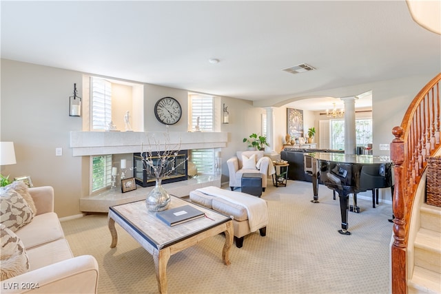 living room with light carpet, decorative columns, a wealth of natural light, and a notable chandelier