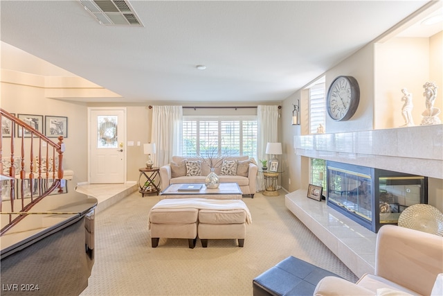 living room featuring a tiled fireplace and light carpet