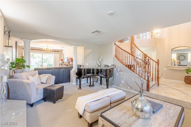 carpeted living room with a notable chandelier and decorative columns