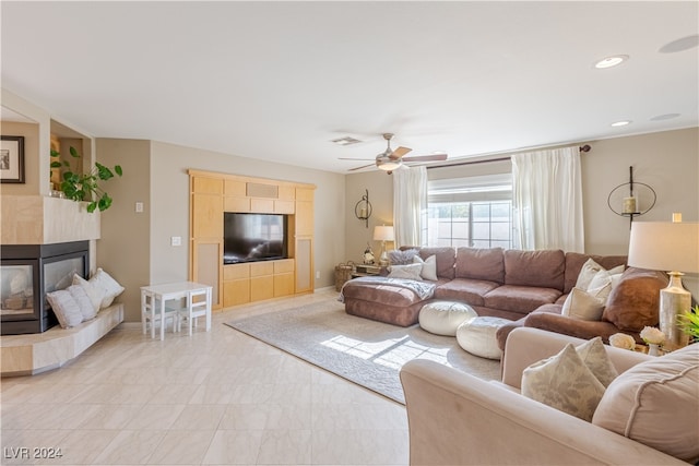 living room featuring a tile fireplace and ceiling fan