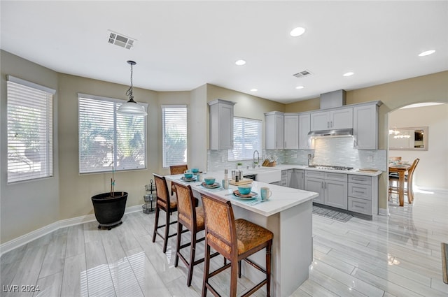 kitchen with plenty of natural light, gray cabinets, hanging light fixtures, and a breakfast bar