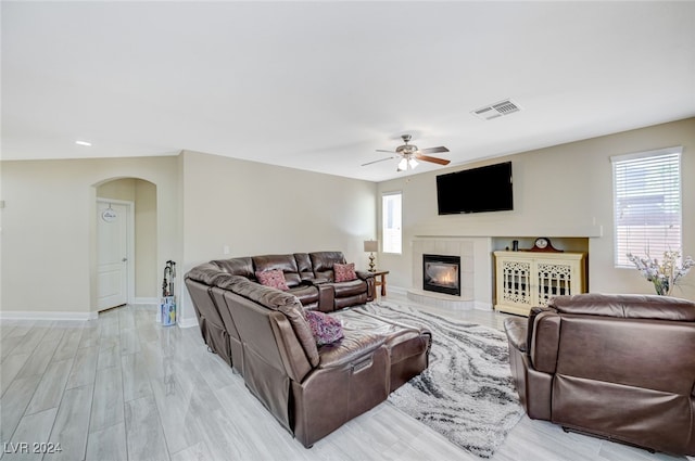 living room with ceiling fan, a fireplace, and light wood-type flooring