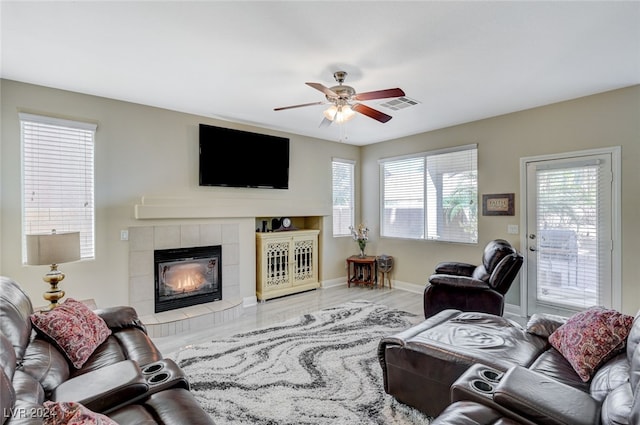 living room featuring hardwood / wood-style flooring, ceiling fan, and a tiled fireplace