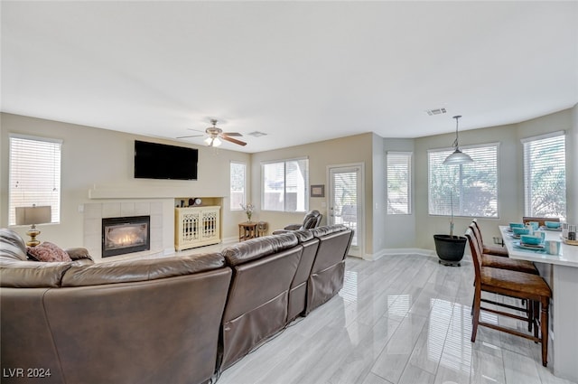 living room featuring a fireplace, ceiling fan, and light hardwood / wood-style flooring