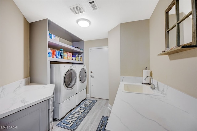 clothes washing area featuring light hardwood / wood-style floors, independent washer and dryer, and sink