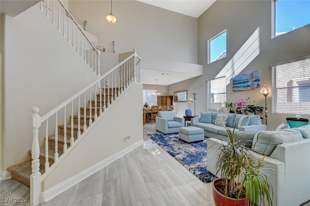 living room with plenty of natural light, a towering ceiling, and hardwood / wood-style floors