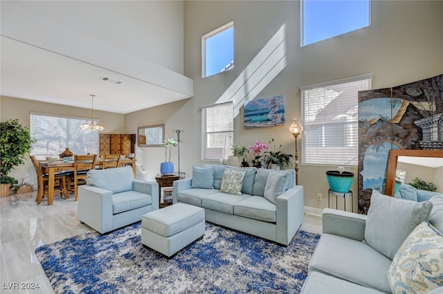 living room featuring a chandelier, a towering ceiling, and hardwood / wood-style flooring