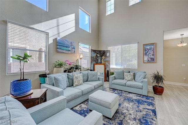 living room with a wealth of natural light, hardwood / wood-style floors, and a towering ceiling