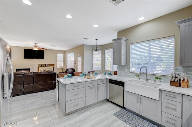 kitchen featuring backsplash, hanging light fixtures, sink, appliances with stainless steel finishes, and kitchen peninsula