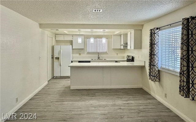 kitchen featuring white cabinets, white refrigerator with ice dispenser, kitchen peninsula, and electric stove