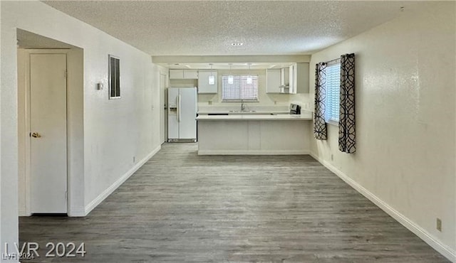 kitchen featuring sink, kitchen peninsula, dark hardwood / wood-style floors, white fridge with ice dispenser, and white cabinetry