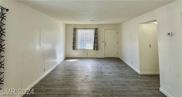 unfurnished room with a textured ceiling and dark hardwood / wood-style floors