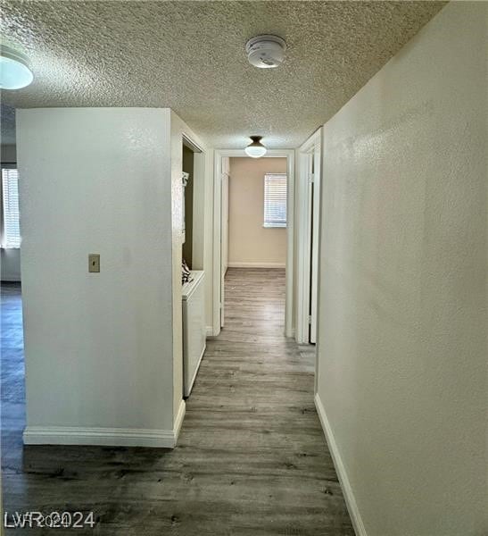 hallway with a textured ceiling and dark wood-type flooring