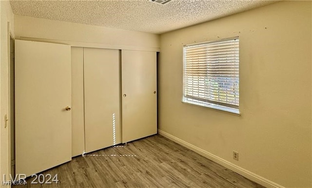 unfurnished bedroom with a closet, a textured ceiling, and light hardwood / wood-style flooring