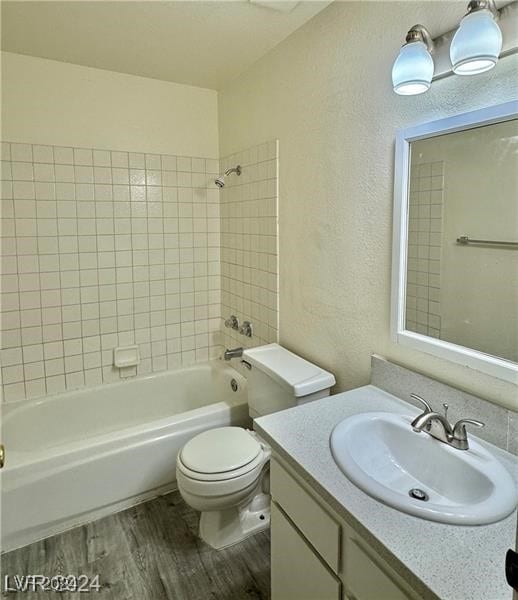 full bathroom featuring vanity, toilet, wood-type flooring, and tiled shower / bath