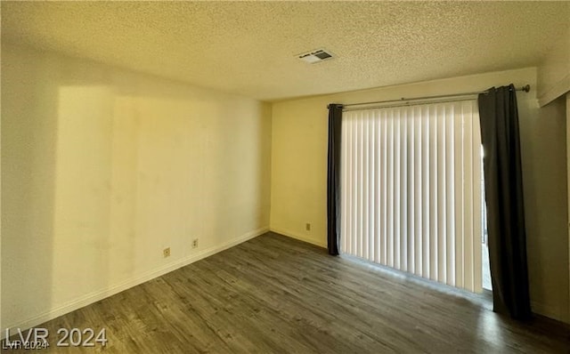 spare room with dark wood-type flooring and a textured ceiling