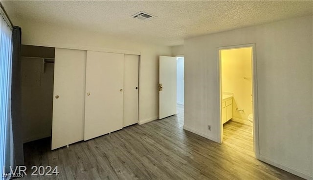 unfurnished bedroom featuring hardwood / wood-style flooring, a textured ceiling, and a closet