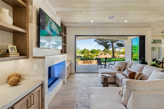 living room featuring light hardwood / wood-style floors, wooden ceiling, a fireplace, and built in features