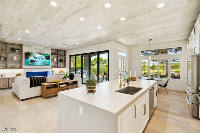 kitchen featuring a center island with sink, white cabinetry, hanging light fixtures, and sink