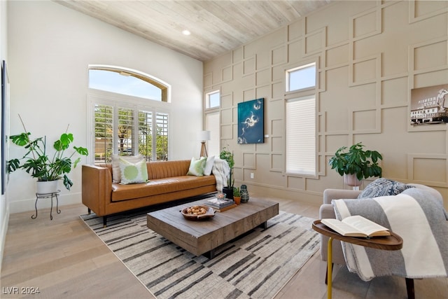 living room with light wood-type flooring, a towering ceiling, and wooden ceiling