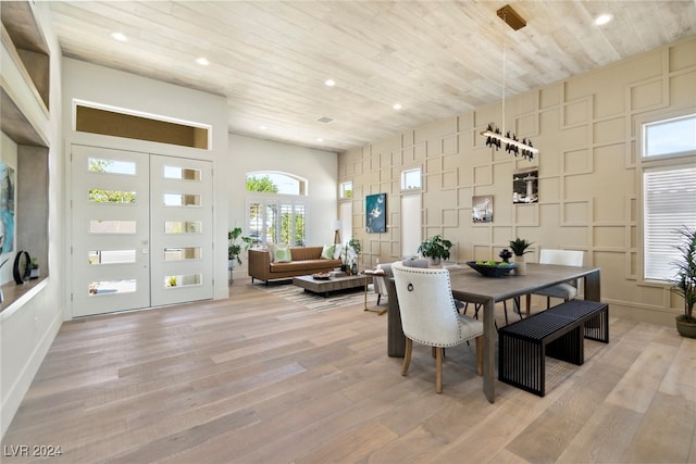 dining space featuring light hardwood / wood-style flooring, wood ceiling, and a high ceiling