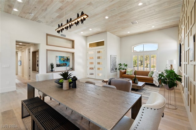 dining room featuring wood ceiling, a high ceiling, and light hardwood / wood-style flooring