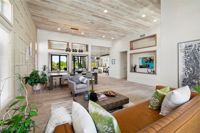 living room with a chandelier, wooden ceiling, a towering ceiling, and light hardwood / wood-style flooring