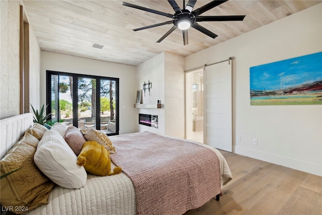 bedroom featuring access to exterior, ceiling fan, a barn door, light hardwood / wood-style floors, and wood ceiling