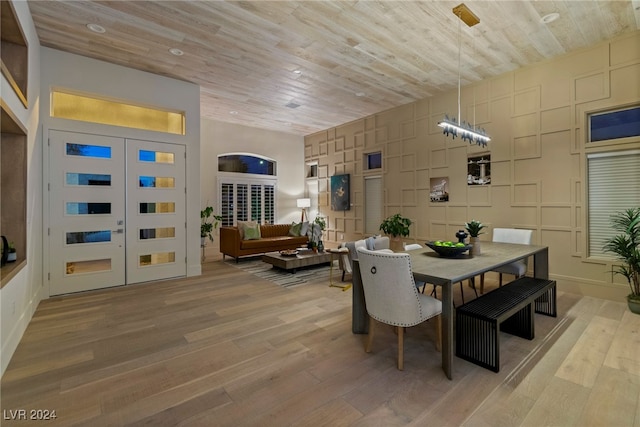 dining room featuring french doors, light hardwood / wood-style floors, and wood ceiling