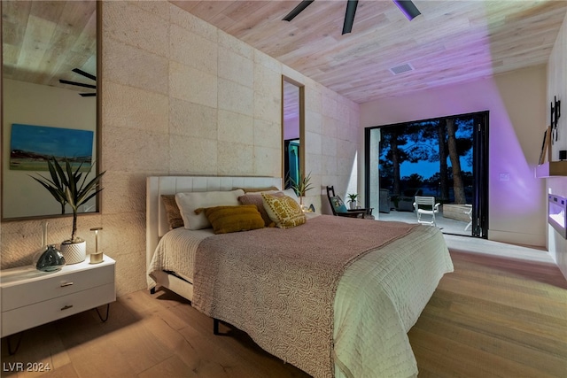 bedroom with light hardwood / wood-style floors, ceiling fan, wooden ceiling, and tile walls