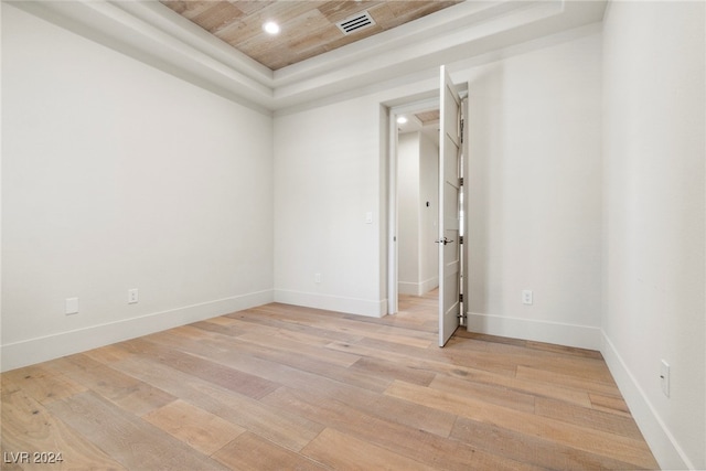 unfurnished room featuring a tray ceiling, light hardwood / wood-style flooring, and wood ceiling