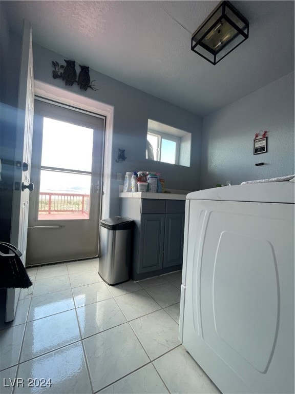 laundry room with washer / clothes dryer, light tile patterned flooring, cabinets, and a textured ceiling