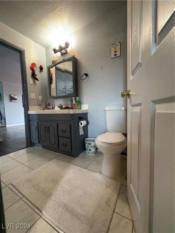 bathroom featuring tile patterned floors, vanity, toilet, and a textured ceiling