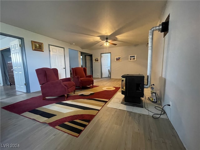 living room featuring a wood stove, ceiling fan, and light wood-type flooring