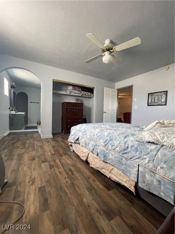 bedroom with ceiling fan, dark wood-type flooring, and a textured ceiling