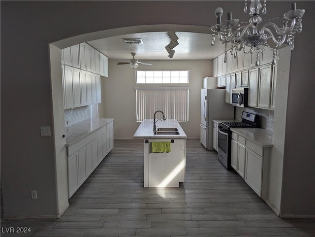 kitchen with a kitchen island with sink, white cabinets, a textured ceiling, and appliances with stainless steel finishes